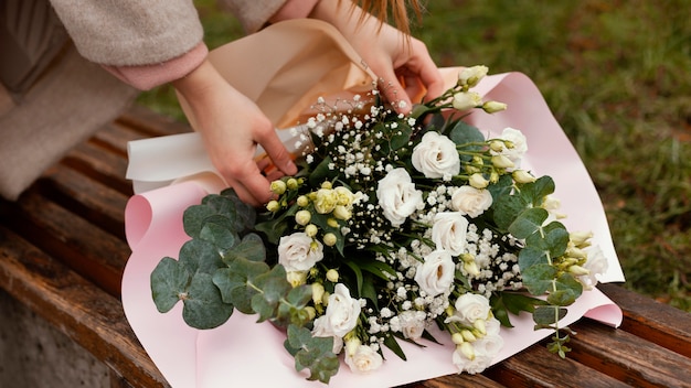 Top view of elegant woman fixing bouquet of flowers outdoors