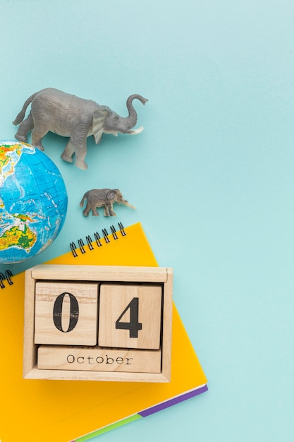 Vista dall'alto di figurine di elefanti con pianeta terra e taccuino per la giornata degli animali