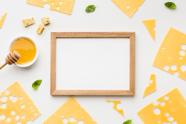 Top view emmental cheese slices with honey and wooden frame