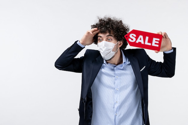 Top view of emotional confused business person in suit and wearing his mask showing sale inscription on white background