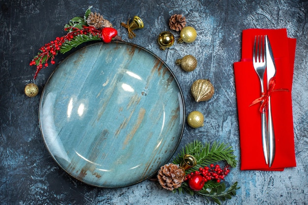 Free photo top view of empty blue plate decorative accessories conifer cone and cutlery set on dark background