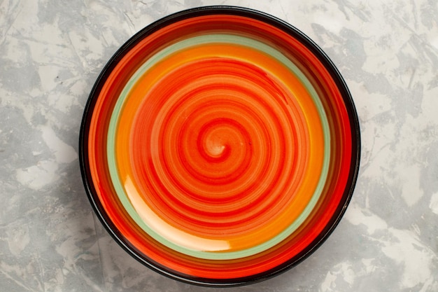 Вид сверху на пустую яркую тарелку из оранжевого цвета на белой поверхности