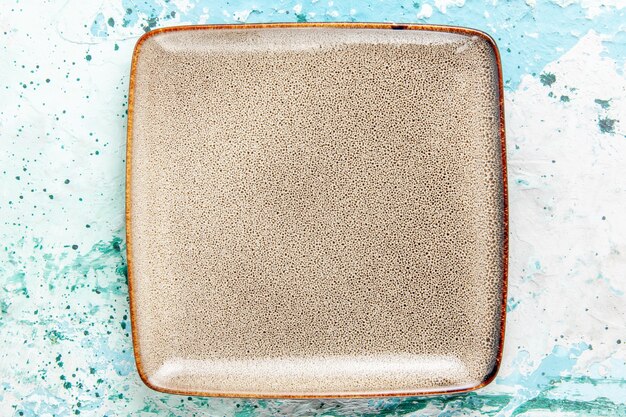 Top view empty brown plate square formed on light-blue background kitchen food plate cutlery