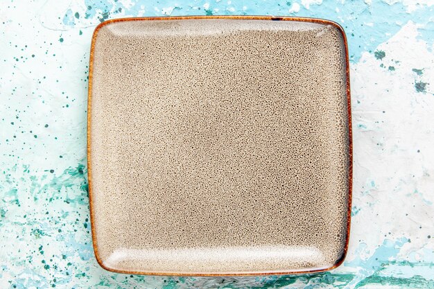 Вид сверху пустая коричневая квадратная тарелка, образованная на голубом фоне, кухонная тарелка для еды, столовые приборы