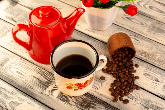 Top view of empty cup with red kettle brown coffee seeds and flowers on the wooden desk