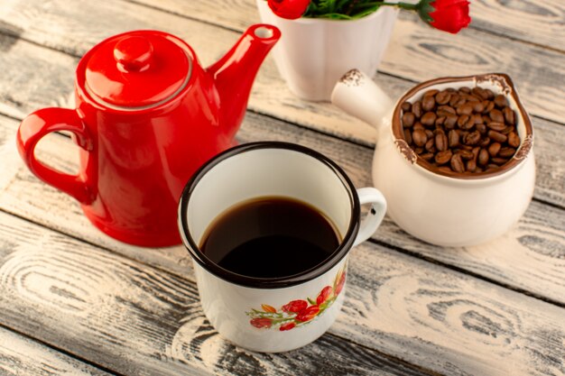 Top view of empty cup with red kettle brown coffee seeds and flowers on the wooden desk