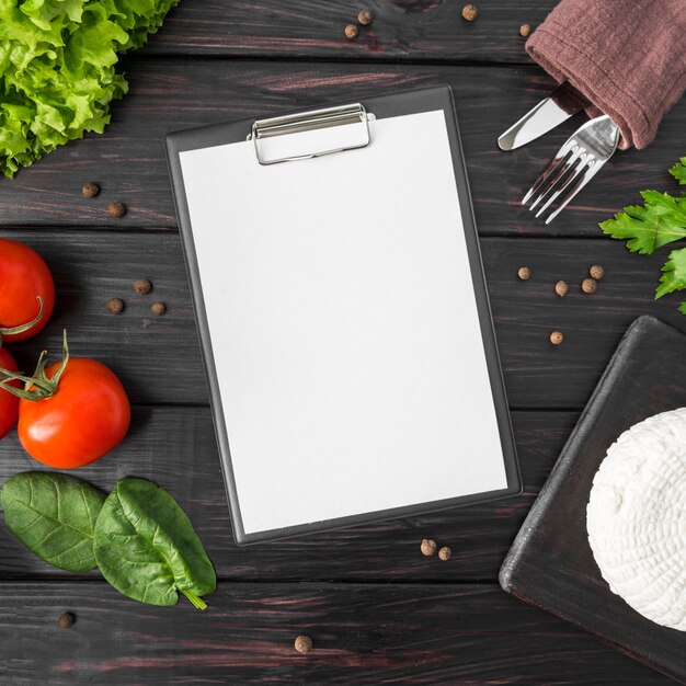 Top view of empty menu with tomatoes and spinach