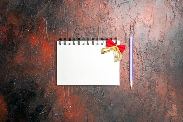 Top view empty open notepad with bow and pencil