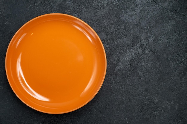 Free photo top view empty orange plate glass made on dark surface