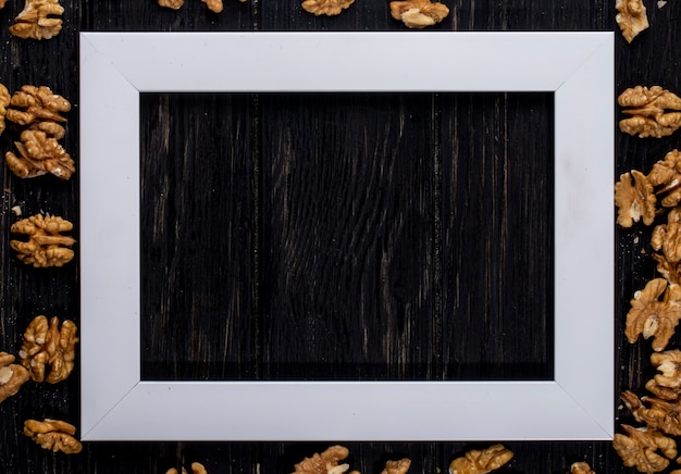 Free photo top view of an empty picture frame with walnuts on wooden