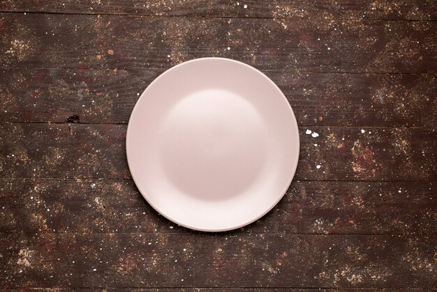 Top view of empty pink plate isolated on brown rustic, wood plate wooden