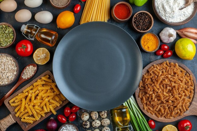 Вид сверху на пустую тарелку с яйцами, помидорами, приправами и итальянской пастой на темном фоне, цвет овощной кухни, фруктовая еда