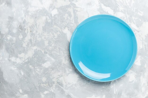 Вид сверху пустая круглая тарелка синего цвета на белой поверхности