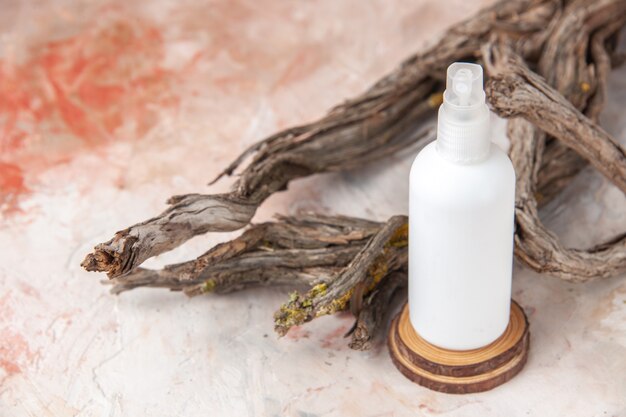 Free photo top view empty spray bottle on wood board tree branch on nude background