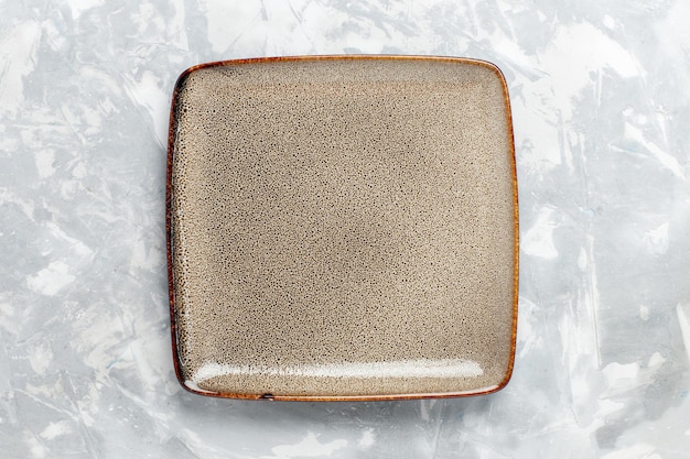 Вид сверху пустая квадратная тарелка коричневого цвета на белой поверхности