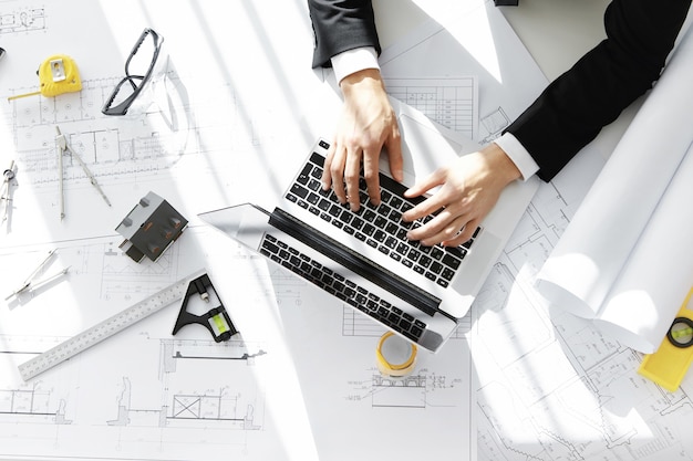 Top view of engineer wearing formal suit working on construction project using laptop