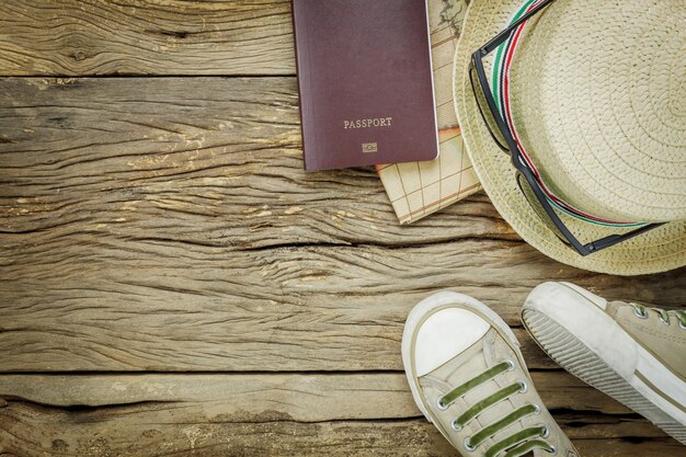 Вид сверху основные предметы для путешествия. Карта паспорт шляпа и человек обуви на деревенском фоне.