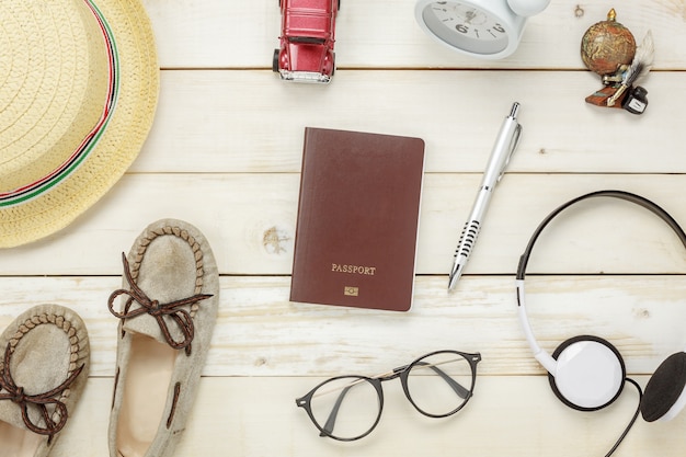 Top view essential travel items.The shoes notebook tree map passport airplane car eyeglasses on rustic  wooden background.