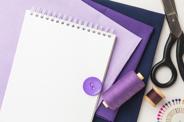 Top view of fabrics with notebook and thread