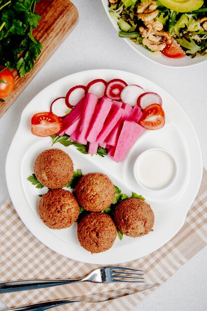 Top view of falafel with fresh vegetables on table