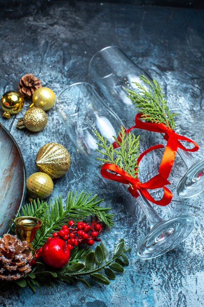 Top view of fallen glass goblets with red ribbon fir branches decoration accessories on dark background