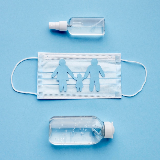 Top view of family made of paper with hand sanitizer and medical mask