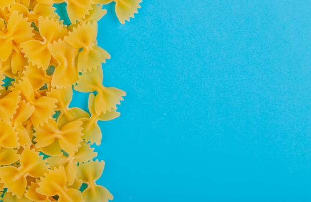 Top view of farfalle pasta on blue surface with copy space