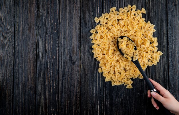 Top view farfalle pasta on the right with copy space on black wooden background