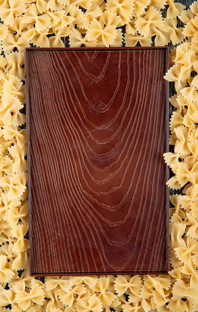 Top view farfalle pasta with copy space on black wooden background