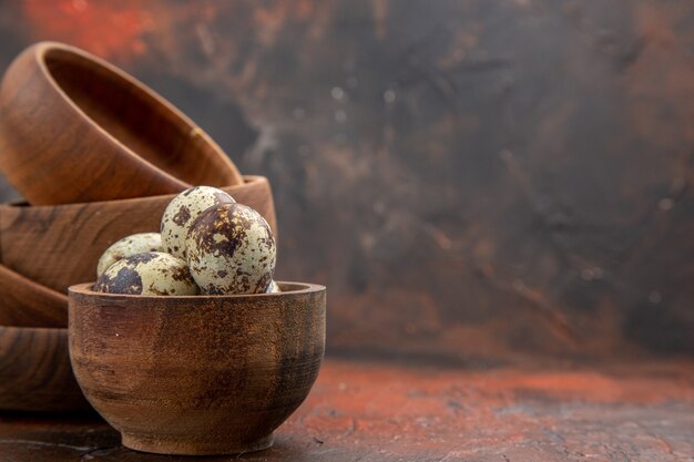 Top view of farm fresh eggs in wooden bowls on the the right side on a brown background