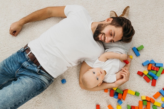 Foto gratuita vista dall'alto di padre e bambino a casa con i giocattoli