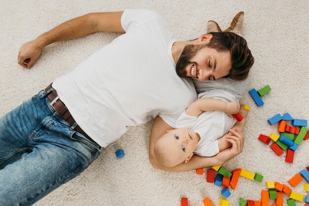 Top view of father and baby at home with toys
