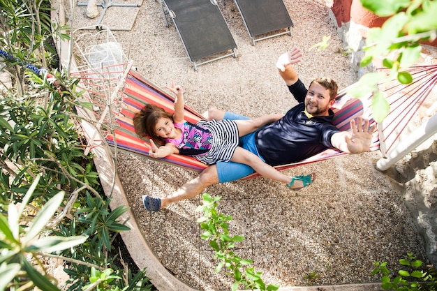 Top view of father and daughter resting on a hammock