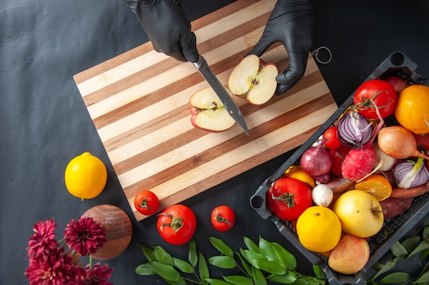 Top view female cook cutting apple on dark surface