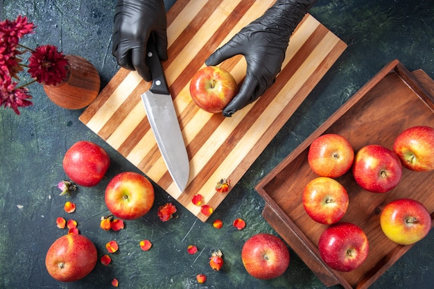 暗い表面でリンゴを切る女性料理人の上面図