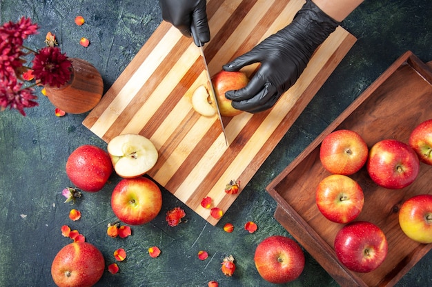 灰色の表面にリンゴを切る女性料理人の上面図