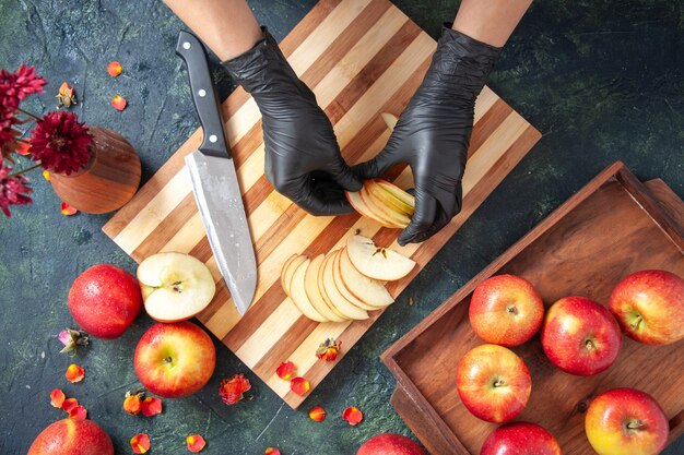 Top view female cook cutting apples on gray surface