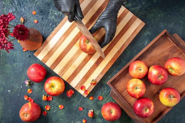 Free photo top view female cook cutting apples on gray surface