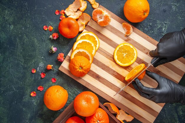 Top view female cook cutting orange on gray surface