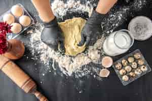 Бесплатное фото Вид сверху женщина-повар раскатывает тесто на темной поверхности