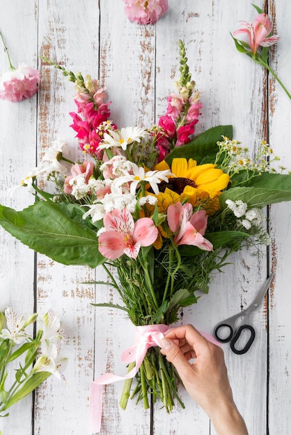 Free photo top view of female hand preparing bouquet of flowers