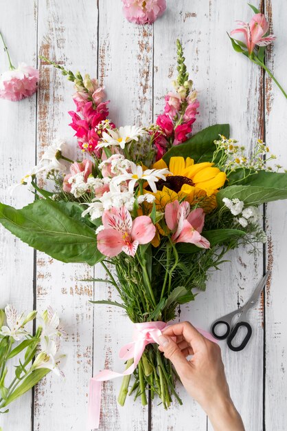 Top view of female hand preparing bouquet of flowers