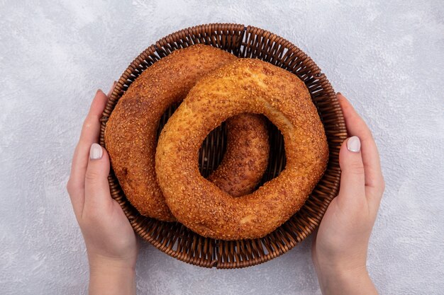 Top view of female hands holding a bucket with traditional turkish bagel on a white background