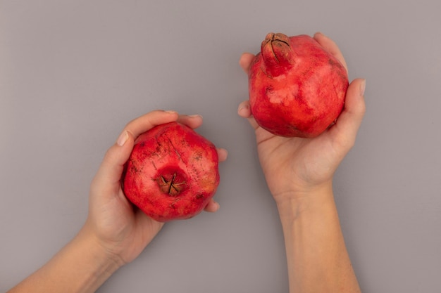 Top view of female hands holding fresh red pomegranates