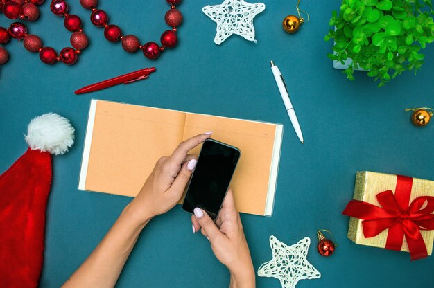 The top view of female hands with phone and Christmas decorations