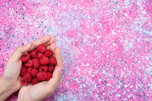 Foto gratuita vista superiore femminile che tiene lampone sulla foto a colori di frutti di bosco sfondo viola