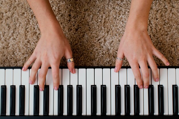Вид сверху на женщину-музыканта, играющую на фортепианной клавиатуре