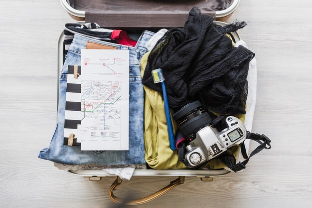 Top view of female's travelling bag with camera, brush and map