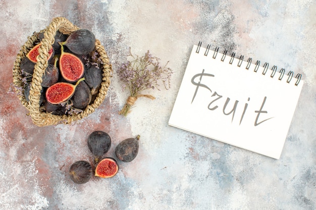 Free photo top view fig basket figs dried flower bunch fruit written on notebook on grey background