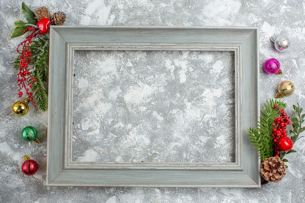 Top view of fir branches conifer cones decoration accessories on the edge of gray wooden frame on ice background